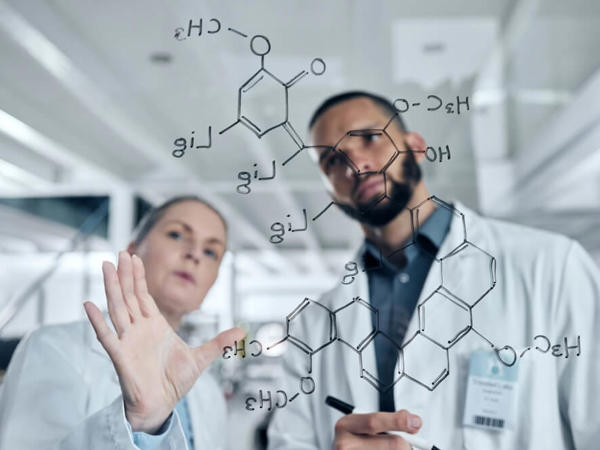 a man and woman in lab coats writing on a glass board